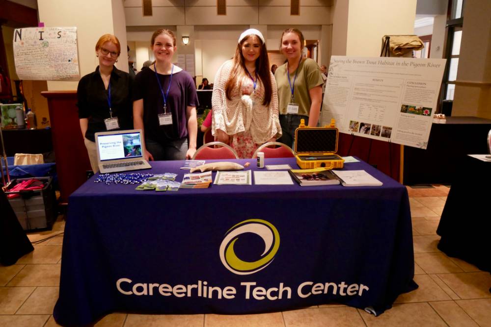Careerline Tech Center students pose by their project table about preserving the pigeon river